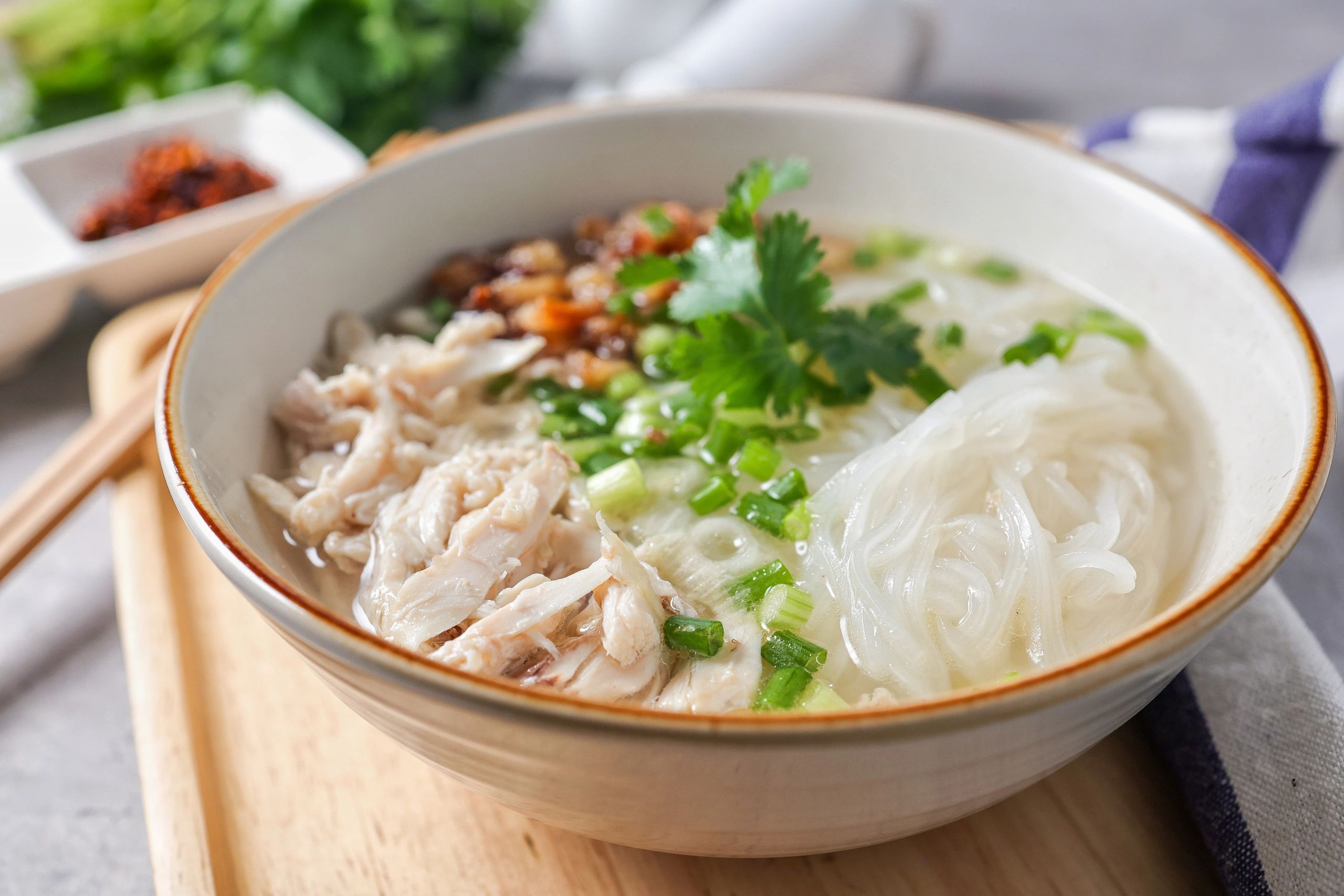 Clear chicken noodle soup with rice noodles and chopsticks