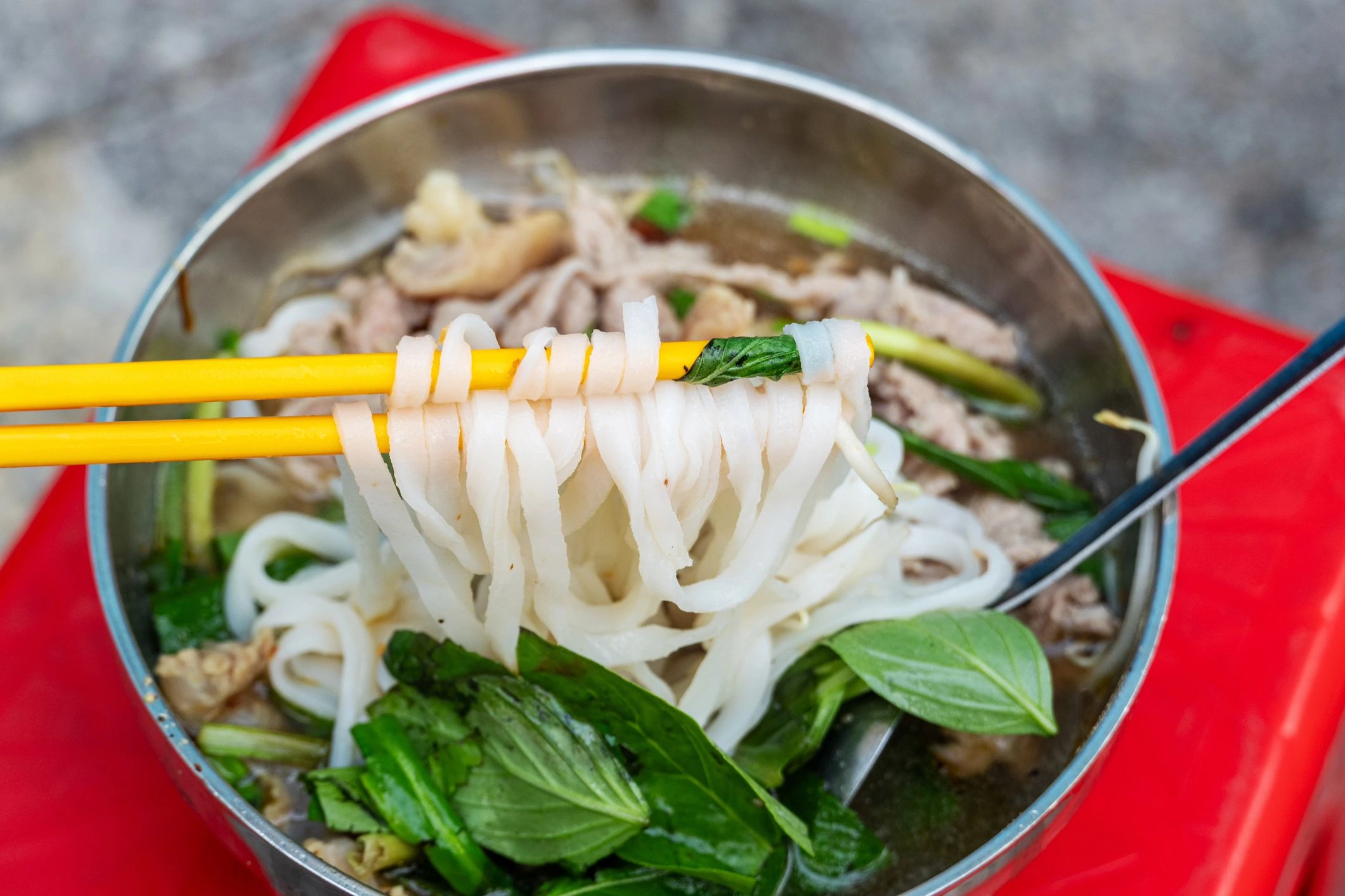 Vietnamese noodle soup with herbs and rice noodles close up