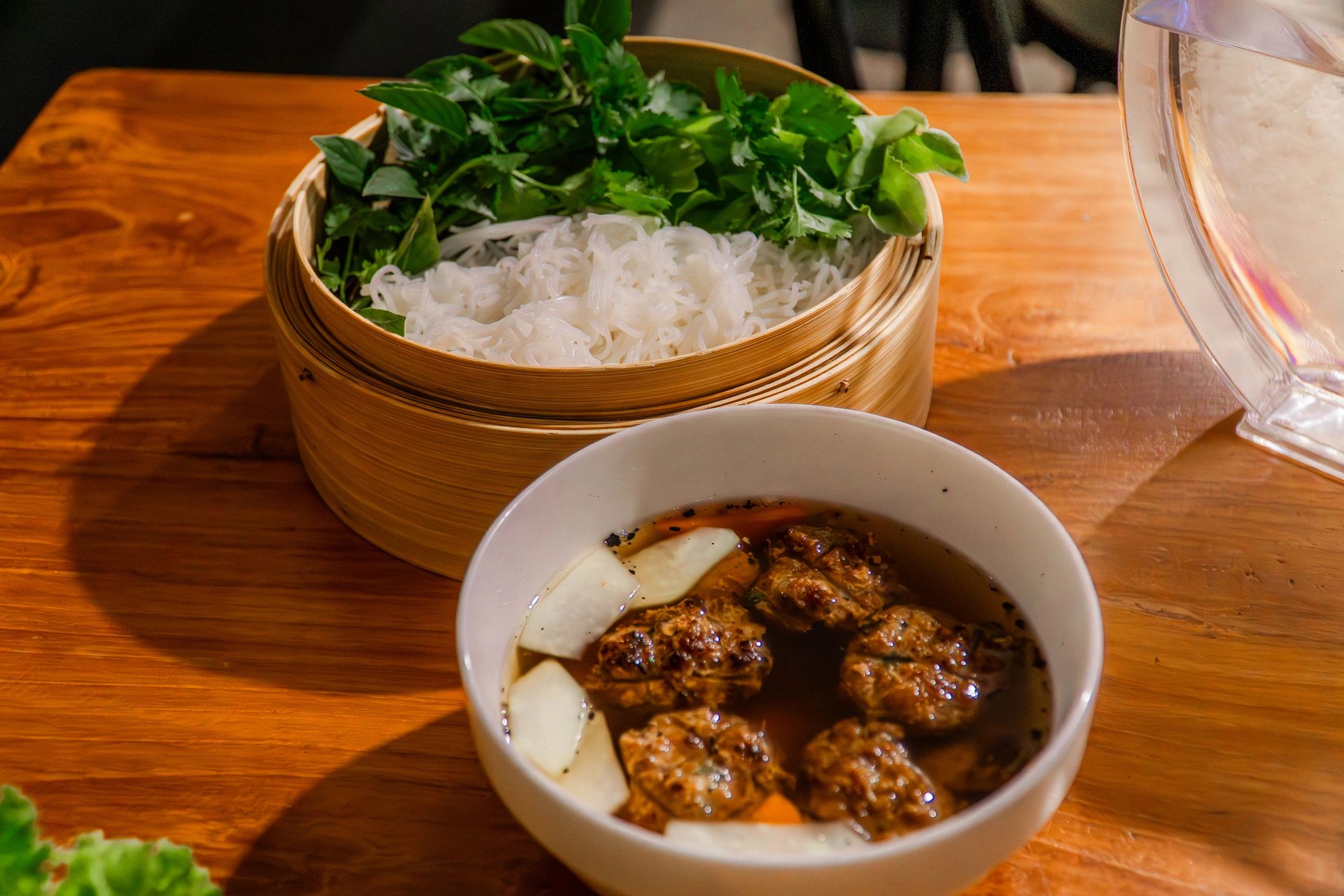 Vietnamese noodle dish served with herbs on a rustic table